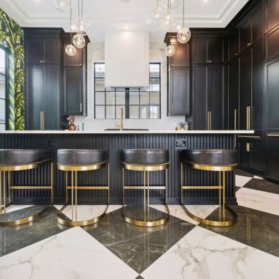 checkered tile floors in a large kitchen with black cabinets and leather stools 